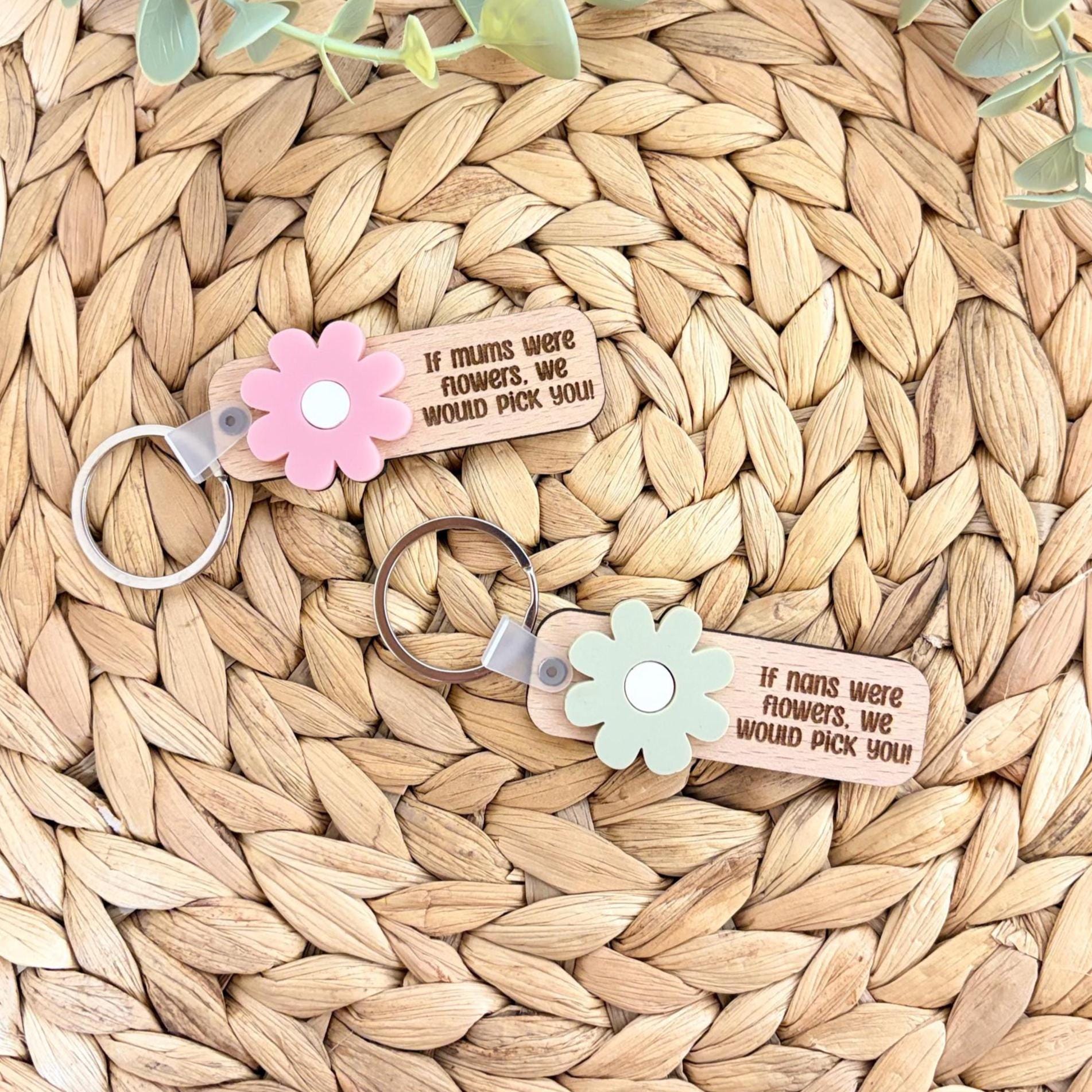 May include: Two wooden keyrings with flower details. One has a pink flower, the other a mint green flower. Each keyring has the text "If mums were flowers, we would pick you!" and "If nans were flowers, we would pick you!"